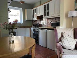 a kitchen with a table and a table and a chair at Lovely 2 bedroom house overlooking park, Free parking in Belfast
