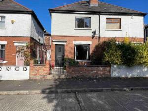 uma casa branca com uma porta preta numa rua em Lovely 2 bedroom house overlooking park, Free parking em Belfast