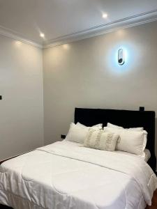 1 dormitorio con 1 cama blanca grande con almohadas blancas en Edge Residences Nalya en Kampala