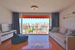 Una sala de estar con un sofá y una ventana grande. en Manhattan View with pool, en Benidorm