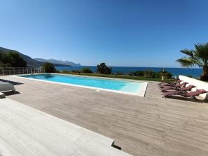a swimming pool with chairs and the ocean in the background at Villa Flo in Castellammare del Golfo