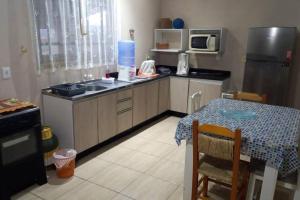 a small kitchen with a table and a refrigerator at Casa privada - Balneário Gaivota-SC 150 metros do mar in Sombrio