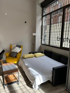 a bedroom with a large bed and a yellow chair at Estudio céntrico zona palacio in Madrid