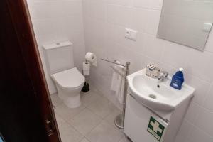 La salle de bains blanche est pourvue de toilettes et d'un lavabo. dans l'établissement Casa Angulosa, à Covilhã
