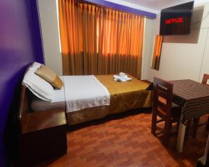 ein Hotelzimmer mit einem Bett, einem Tisch und einem Stuhl in der Unterkunft Hotel California in Chachapoyas