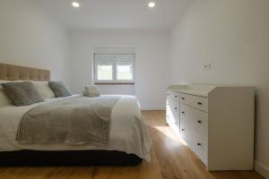 a white bedroom with a bed and a dresser at Apartamento T3 em Lisboa/ Queluz in Queluz