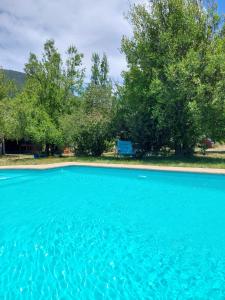 a pool of blue water with trees in the background at Peumayenlodge Cabaña moderna in Antuco