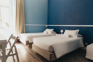 two beds in a room with blue walls at Hotel Leiria Classic in Leiria