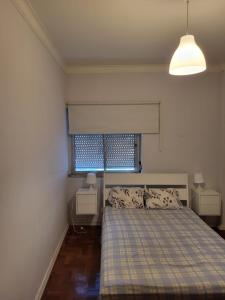 een slaapkamer met een bed met 2 nachtkastjes en een raam bij K House in Odivelas