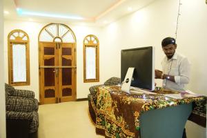 a man standing at a desk with a laptop computer at Sobia Villa in Jaffna