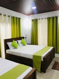 two beds in a room with green curtains at GreenSenz Resort & Hostel-Sigiriya in Sigiriya