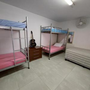 a room with three bunk beds and a guitar at Hostel Muarama in Passos