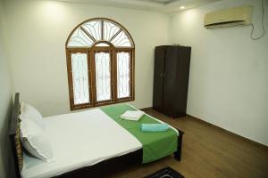 a bedroom with a white bed and a window at Sobia Villa in Jaffna