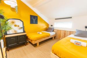 a yellow room with two beds and a mirror at SURF HOSTEL BIARRITZ in Biarritz