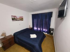1 dormitorio con 1 cama azul y TV en Hotel Belgrano en Villa Carlos Paz