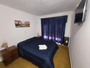 Un dormitorio con una cama azul y un televisor. en Hotel Belgrano, en Villa Carlos Paz