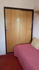 1 dormitorio con 1 cama y puerta de madera en Departamento a 200mts de la playa en Miramar