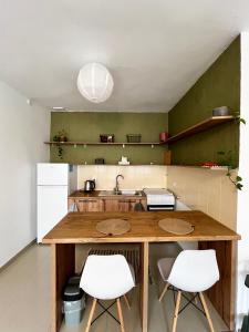 a kitchen with a wooden counter and two white chairs at Drd Pristine Apartment in Pristina