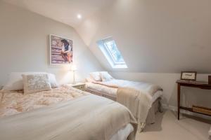 a attic room with two beds and a window at Dedham Vale Cottage with Swimming Pool - Yew Tree Barn in Higham