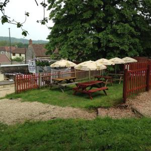 a group of picnic tables with umbrellas next to a fence at The Crown Inn - By Whitney Inns in Keynsham