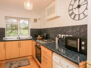 a kitchen with wooden cabinets and a clock on the wall at Time and Tide in Carnforth