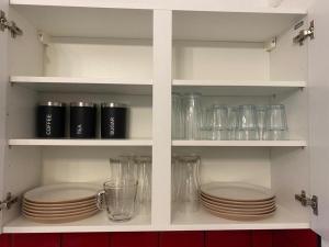 a kitchen shelf with plates and glasses on it at Spacious 4 Bedroom Townhouse in Leeds