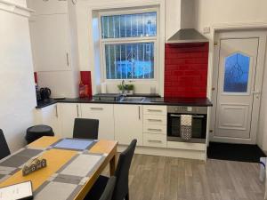 a kitchen with a table and a sink and a stove at Spacious 4 Bedroom Townhouse in Leeds