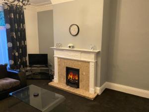 a living room with a fireplace with a clock on the wall at Spacious 4 Bedroom Townhouse in Leeds