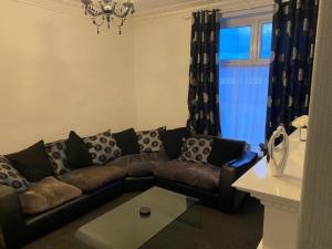 a living room with a couch and a window at Spacious 4 Bedroom Townhouse in Leeds