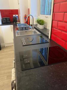 um balcão de cozinha com um lavatório e azulejos vermelhos em Spacious 4 Bedroom Townhouse em Leeds