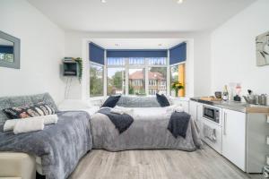 sala de estar con 2 camas y cocina en A Bright Lovely Spacious Studio. en Woodford Green