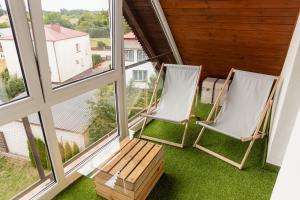 2 Stühle auf einem Balkon mit Fenstern in der Unterkunft Apartament na Górnej in Puńsk