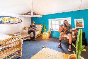 a man and a woman playing a guitar in a living room at SURF HOSTEL BIARRITZ in Biarritz
