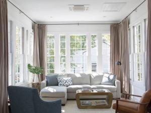 a living room with a white couch and windows at Solarium at Cassa Zoe in Charleston