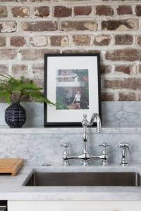 a kitchen sink with a picture on a brick wall at Solarium at Cassa Zoe in Charleston