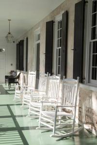 uma fila de cadeiras brancas sentadas num alpendre em Sparrow at Casa Zoe em Charleston