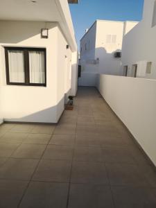 a hallway of a white building with a tile floor at Casa Merlín Arena in Playa Honda