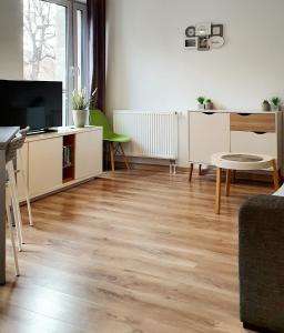 a living room with a wooden floor and a tv at Good Time Apartments Strzelecka C in Poznań
