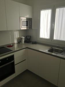 a kitchen with white cabinets and a sink and a microwave at Casa Merlín Arena in Playa Honda
