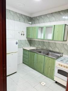 a kitchen with green cabinets and a white appliance at الاصايل 1-طريق الاربعين in Al-Safa