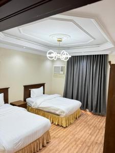a hotel room with two beds and a chandelier at الاصايل 1-طريق الاربعين in Al-Safa +6 photos