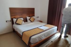 Ein Mann steht in einem Schlafzimmer mit einem großen Bett in der Unterkunft Luxurious & Spacious 4BHK Villa with AC at City Centre, Pearl Stayz in Mysore