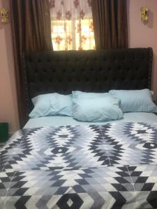 uma cama com um edredão e almofadas preto e branco em Dazzle Hotels and Apartments Riverpark em Rubuchi