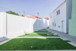 eine Gasse mit einer weißen Wand und einem Stuhl auf dem Gras in der Unterkunft Duplex Apartment near Belém in Lissabon