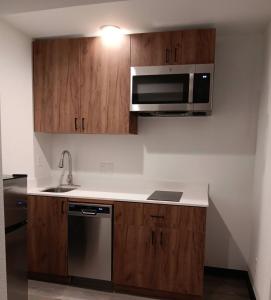 a kitchen with wooden cabinets and a microwave at StateLine Stayovers Extended Stay Hotel in Texarkana