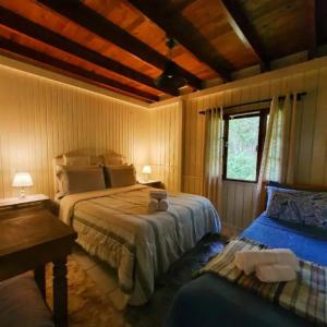 1 Schlafzimmer mit 2 Betten, einem Fenster und einem Sofa in der Unterkunft Chalé Villa das Hortênsias in Annitapolis