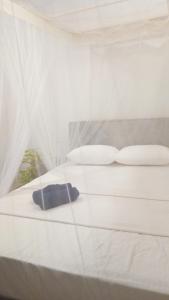 a bed with white sheets and pillows and a window at Venora Hiriketiya in Dickwella