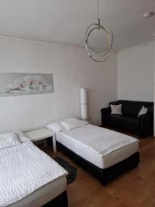 sala de estar con 2 camas y sofá en Orchidea Apartman, en Gödöllő