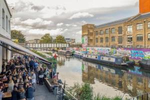 a crowd of people standing next to a river with boats at Refurbished bright and cosy 2 bedroom apartment next to Stratford hot spots in London