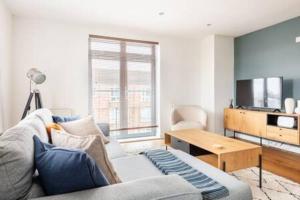 a living room with a couch and a table at Refurbished bright and cosy 2 bedroom apartment next to Stratford hot spots in London